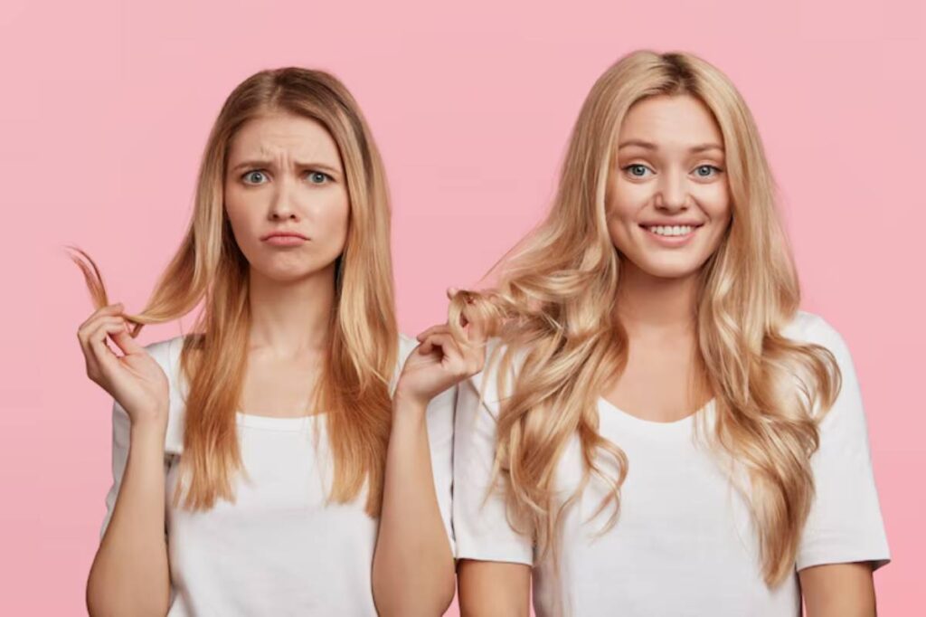 Two women with long hair, one straight and one wavy, both wearing white t-shirts, stand against a pink background.
