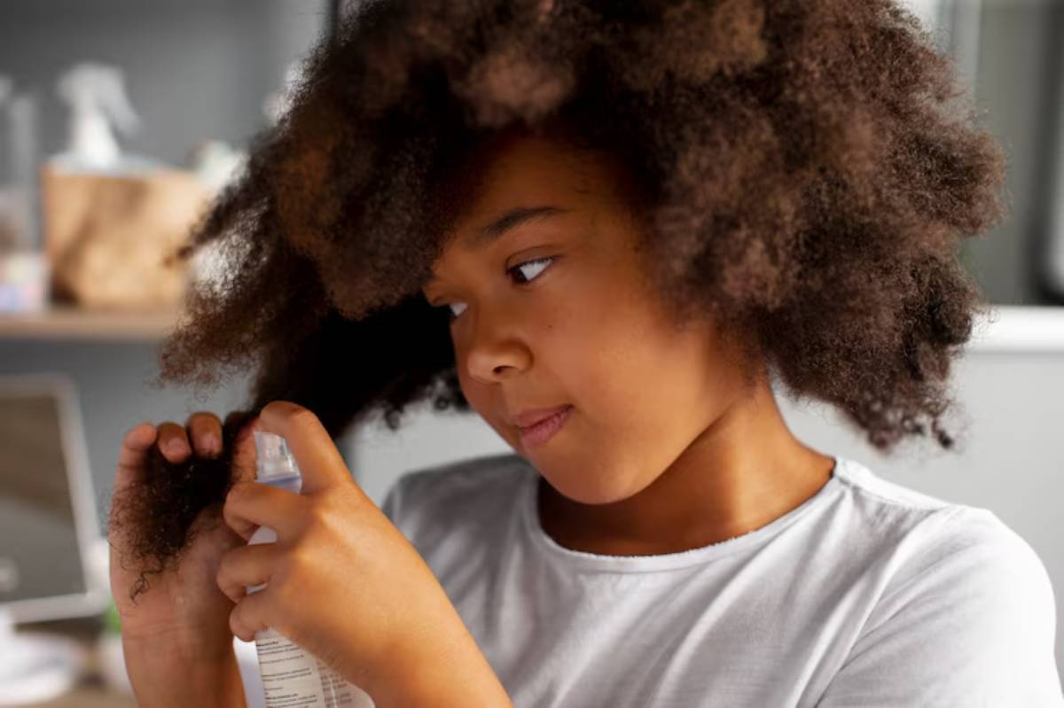A person sprays a hair product onto their curly hair, focusing on moisturizing and styling in a bright, cozy room.